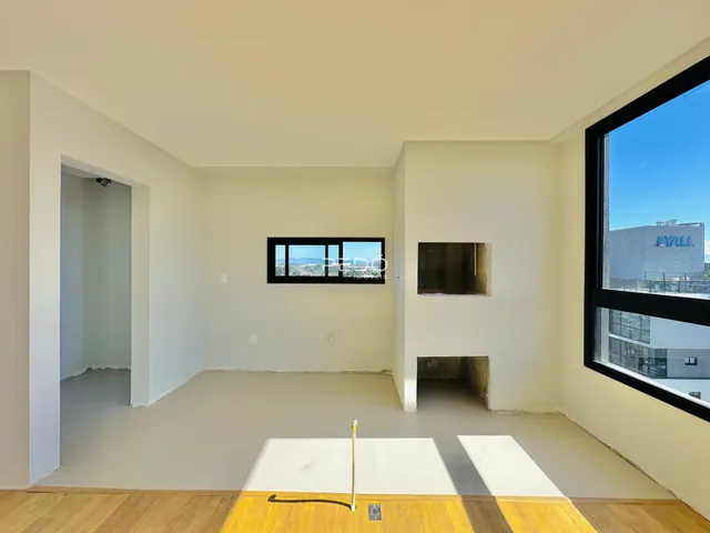 Interior de uma sala com paredes brancas e piso em obra em Lajeado.