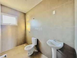 Banheiro com paredes de azulejo claro e louças brancas.