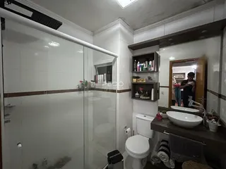 Foto de um banheiro com box de vidro e revestimento branco.