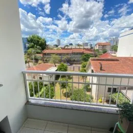 Vista externa de um terraço com vegetação e edifícios ao fundo.