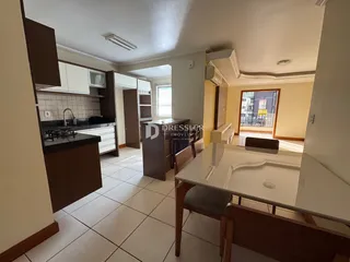 Interior de uma sala de estar com cozinha integrada em um imóvel.