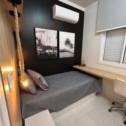 Quarto com cama e paredes claras em um imóvel.