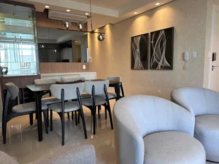 Sala de estar com poltronas claras e piso claro.