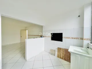 Vista de um corredor interno com piso de cerâmica branca e paredes brancas.