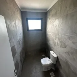 Corredor estreito com um vaso sanitário branco visível na parede.