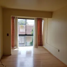 Hall de entrada com piso de madeira e porta de vidro.
