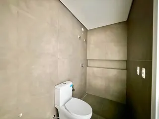 Foto interna de um banheiro com revestimento em tons neutros.