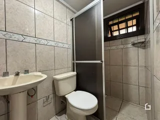 Foto interna de um banheiro com azulejos claros e louças sanitárias.