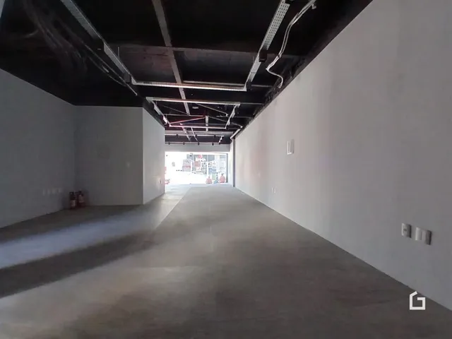 Corredor interno com teto exposto e paredes brancas em um imóvel.