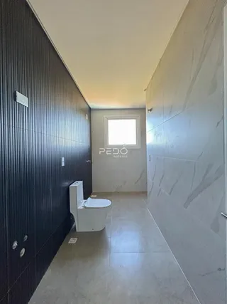 Hall de banheiro com piso de cerâmica e paredes revestidas.