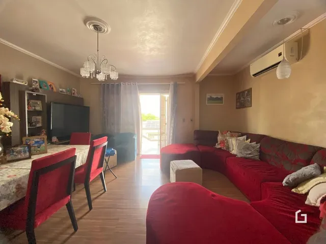 Sala de estar com sofá vermelho e piso de madeira em Lajeado.