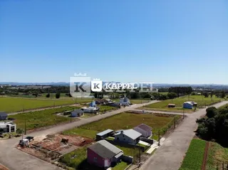 Vista aérea de uma propriedade rural com campos abertos e estruturas dispersas.