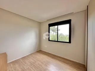 Ambiente interno de uma sala com piso de madeira clara e grande janela.