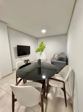 Sala de jantar com mesa redonda e cadeiras brancas em um ambiente claro.
