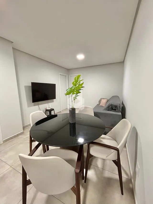 Sala de jantar com mesa redonda e cadeiras brancas em um ambiente claro.