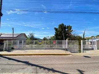 Vista da fachada de uma propriedade em Lajeado, Brasil, com cerca e portão.