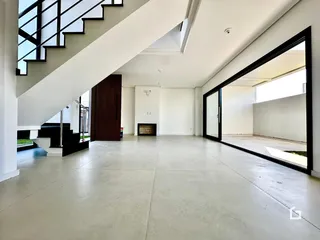 Vista interna de um espaço amplo com teto alto e escadaria moderna.