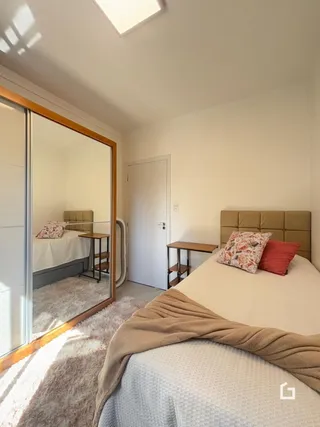 Quarto com cama e espelho em ambiente interno.