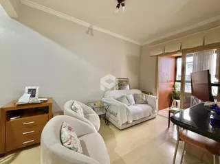Sala de estar com móveis brancos e piso de madeira clara.