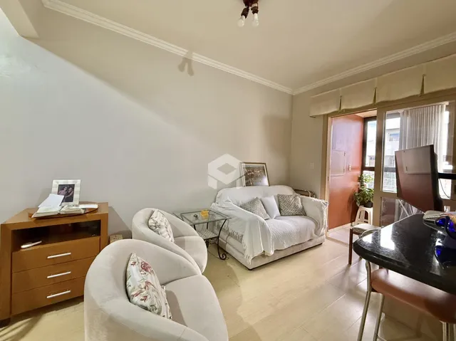 Sala de estar com móveis brancos e piso de madeira clara.