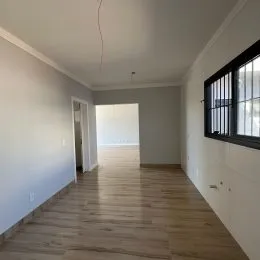 Vista de um corredor interno com paredes claras e piso de madeira.