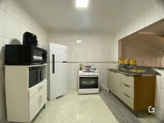 Cozinha com revestimento branco e piso cerâmico claro.
