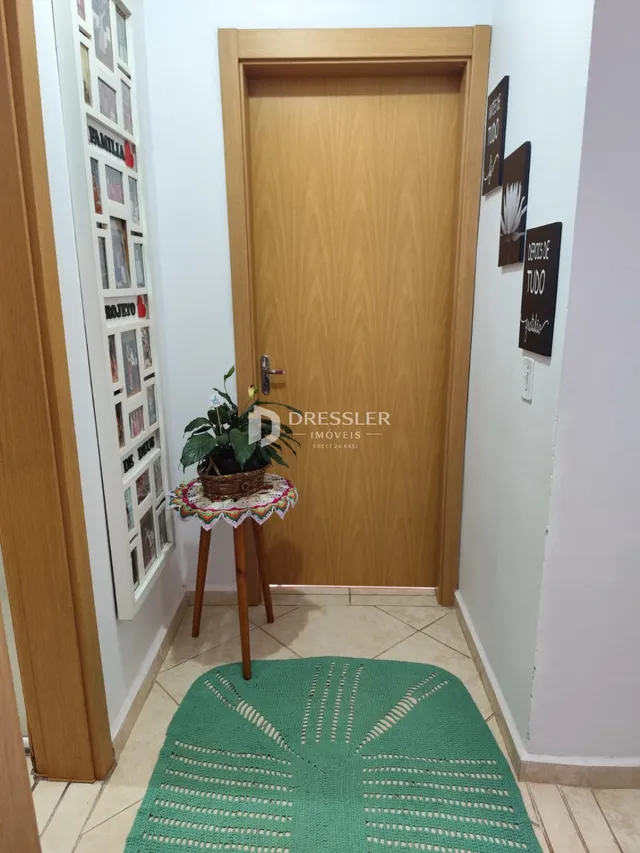 Foto de uma entrada com porta de madeira e tapete verde em uma residência.