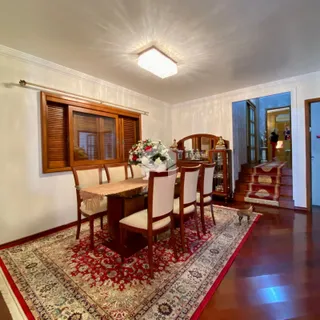 Sala de jantar com móveis de madeira e tapete estampado.