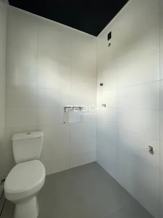 Foto de um banheiro com piso e paredes brancas.
