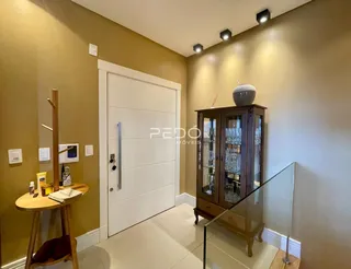 Hall de entrada com porta branca e móveis de madeira na residência.