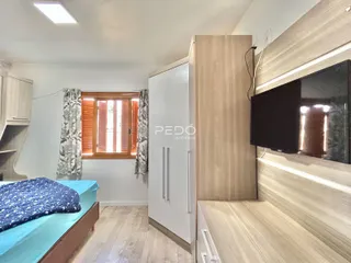 Quarto com cama e armário de madeira em um imóvel no Brasil.