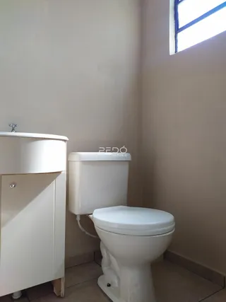 Uma foto mostra um banheiro com um armário e um vaso sanitário brancos.