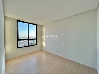 Sala com piso de madeira e grande janela.
