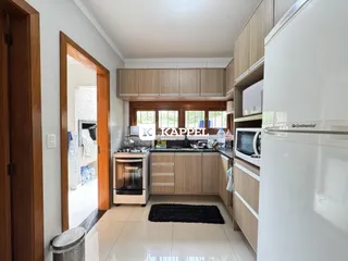 Cozinha moderna com armários de madeira clara e eletrodomésticos brancos.