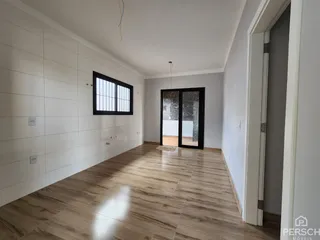 Corredor com piso de madeira e paredes brancas em um imóvel.