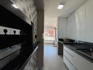 Cozinha moderna com armários brancos e bancadas escuras.