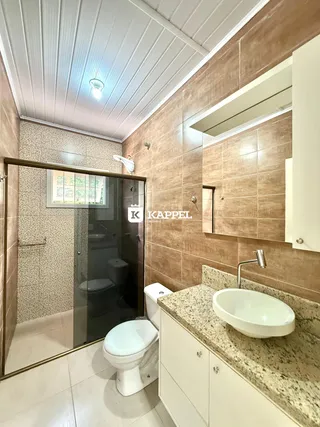 Banheiro com revestimento de azulejos marrons e bancada de granito.