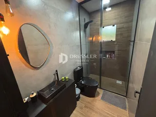 Foto de um banheiro com box de vidro e bancada escura.