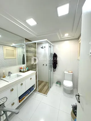 Banheiro moderno com box de vidro e piso branco.