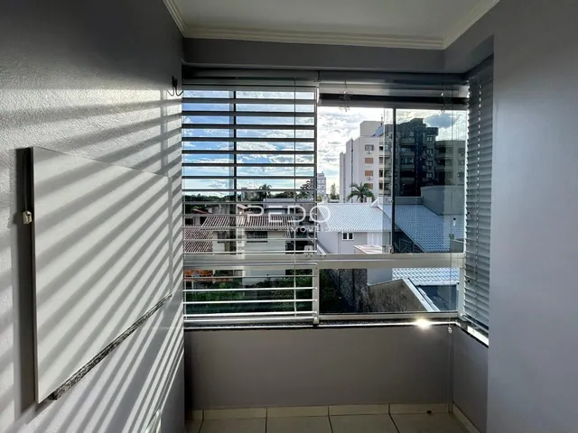 Vista de uma janela interna com persianas e vista para edifícios vizinhos.