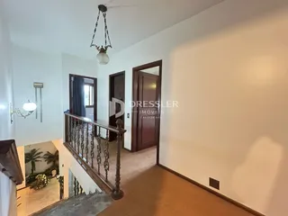Vista do corredor com escadaria e portas de madeira em uma residência.