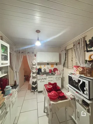 Foto interna de uma cozinha com armários brancos e piso cerâmico.