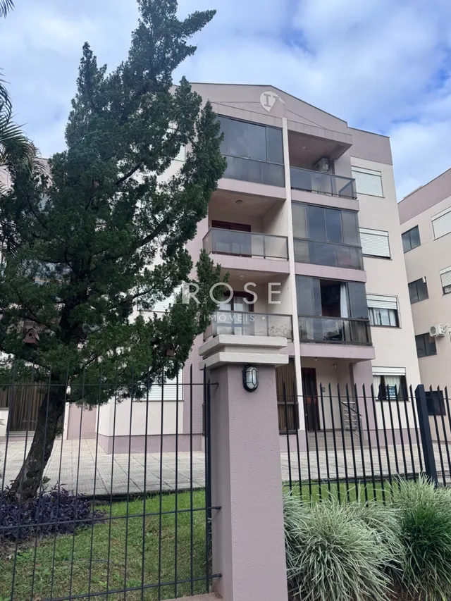 Fachada de um prédio residencial em Lajeado, Brasil, com cerca e jardim na frente.