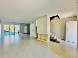 Sala de estar ampla com piso claro e portas de vidro que dão acesso ao exterior.