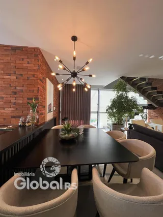 Sala de jantar com mesa escura e cadeiras em um ambiente com parede de tijolos.
