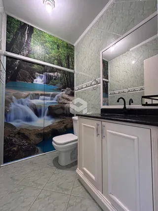 Foto de um banheiro com revestimento de azulejo e uma parede com imagem de cachoeira.