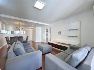 Sala de estar moderna com sofás cinzas e piso de madeira.