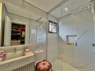 Banheiro moderno com revestimento em mármore branco e box de vidro.
