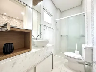 Banheiro moderno com box de vidro e revestimento branco.
