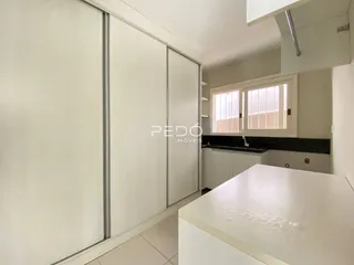 Vista interna de um ambiente com armários brancos e bancada.